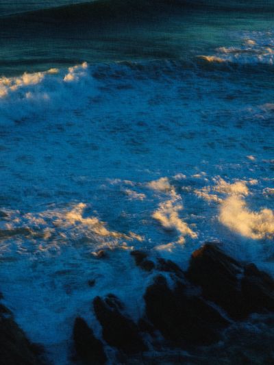 Sunlit surf breaking over dark rocks.