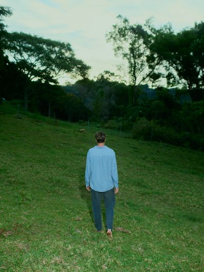 Figure walking through a green pasture at dusk.